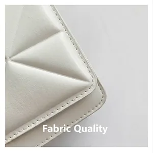 Close-up of white geometric quilted leather detail and fine stitching on a square bag