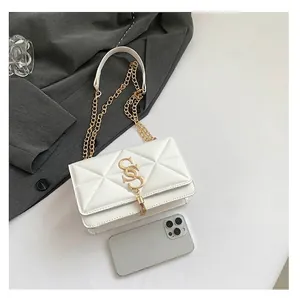 Detail showing white geometric quilted bag with gold hardware and phone for size reference