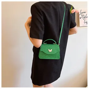 Détail du sac à main papillon vert émeraude avec texture brillante et poignée chic