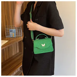 Détail du sac à bandoulière vert brillant avec boucle papillon dorée élégante