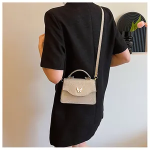 Détail du sac à paillettes champagne doré avec une boucle papillon sur la bandoulière chic