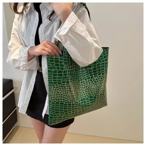 Detail of a bright green tote bag with crocodile texture and glossy patent finish