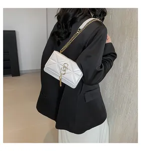 Macro detail of white quilted crossbody bag with gold chain strap and tassel