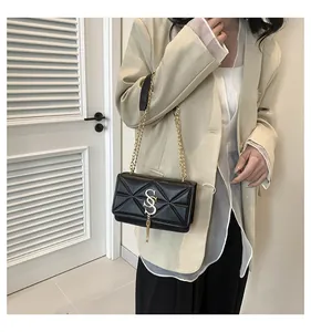 Detail of black quilted crossbody bag with gold chain strap and stylish tassel detail
