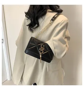 Detail of black quilted shoulder bag with gold 'S' charm on beige blazer back