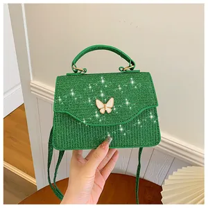 Détail du mini sac vert texturé avec boucle papillon blanche et accents dorés