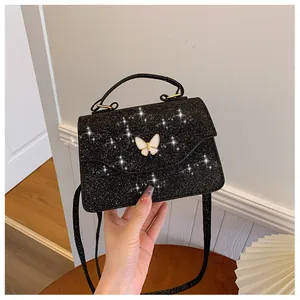 Détail d'un sac noir scintillant avec boucle papillon blanche et rabat en forme de vague
