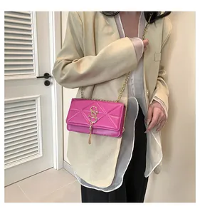 Close-up of bright pink leather crossbody bag with geometric texture and gold tassel charm