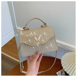 Détail du petit sac doré à paillettes avec fermoir papillon et bandoulière amovible