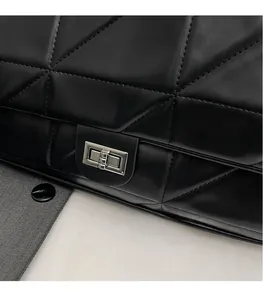 Detail von silbernem Drehverschluss und Rautensteppung auf schwarzer Ledertasche
