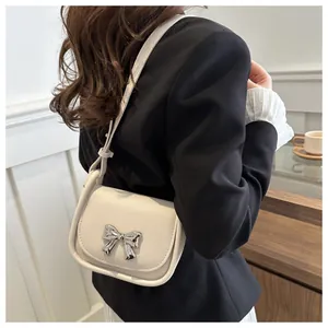 Détail du sac selle crème avec nœud argenté et texture en similicuir lisse et doux