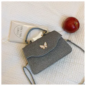 Détail du sac à main gris scintillant avec fermoir papillon blanc et rabat en forme de V