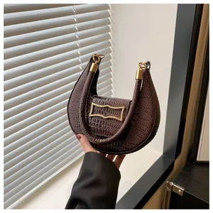 Détail du sac croissant marron foncé avec motif pierre, boucle dorée et finitions métal