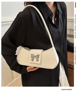 Close-up of white shoulder bag featuring a decorative silver butterfly metal hardware