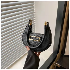 Détail du sac croissant noir avec texture crocodile et boucles métalliques dorées
