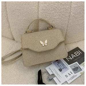 Vue détaillée du sac à main pailleté champagne avec décoration papillon en métal