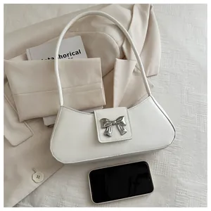 Close-up of a white baguette bag featuring a metallic silver butterfly clasp on leather