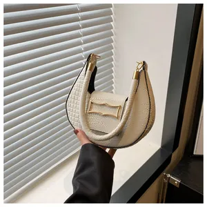 Gros plan détaillé sur la texture crocodile blanche d'un sac hobo avec boucle dorée
