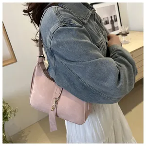 Pink crescent underarm bag with metal buckle detail and adjustable strap on a model