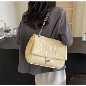 Nahaufnahme der beigen Stepptasche mit silberner Kette und Metall-Drehverschluss-Detail
