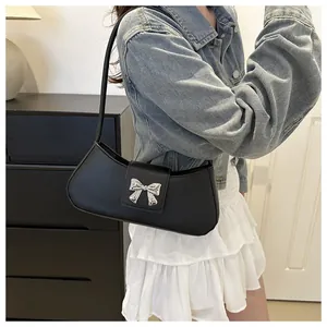 Detail of black PU leather underarm bag with silver butterfly hardware on model