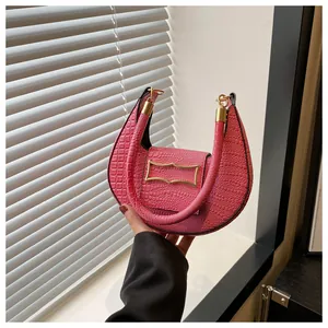 Détail du sac croissant rose montrant la texture crocodile et fermoirs dorés