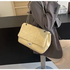 Detail einer hellgelben gesteppten Tote-Bag mit silberner Kette am Model im Anzug