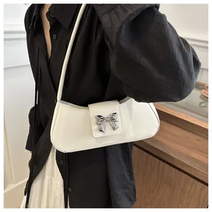 Detail of white baguette bag with silver butterfly buckle on model