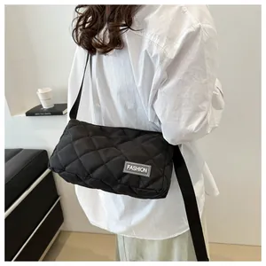 Detail of black quilted crossbody bag with rhombic stitching and fashion logo tag