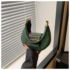 Détail du sac croissant vert avec texture crocodile et boucles dorées