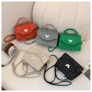 Détail des sacs à main à paillettes avec papillon en cinq couleurs sur fond texturé