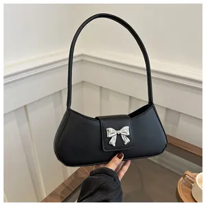 Detailed close-up of a black leather bag featuring a silver butterfly hardware clasp