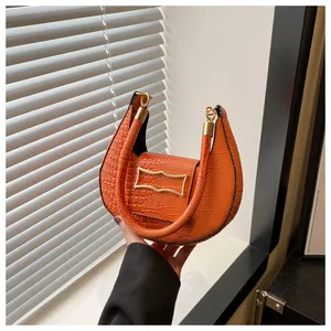 Détail du sac croissant orange avec texture crocodile et finitions métalliques dorées