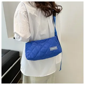 Detail of blue quilted crossbody bag featuring a fashion tag and adjustable strap