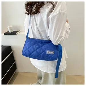 Royal blue quilted nylon shoulder bag shown on model in a minimalist studio setting