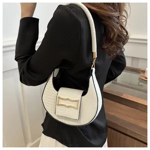 Détail du sac croissant blanc à texture crocodile et boucle dorée à l'épaule