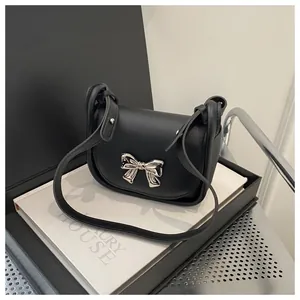 Détail du mini sac bandoulière noir avec boucle de nœud argentée et bandoulière en cuir