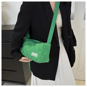 Detail of bright green quilted crossbody bag with white FASHION label on nylon fabric