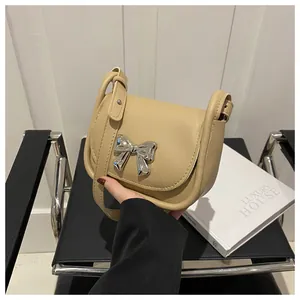 Détail du sac selle beige avec nœud argenté et fermeture à rabat magnétique