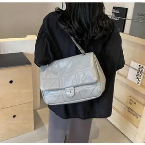 Detail der grauen Stepptasche mit silberner Kette und Metalldrehverschluss am Modell