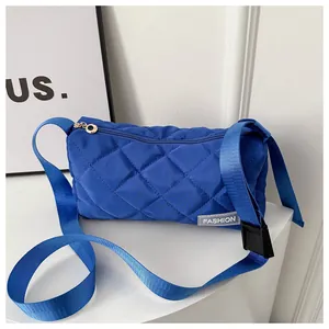 Detail of blue quilted bucket bag showing fabric texture, fashion label and wide strap