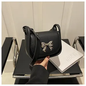 Détail d'un sac selle noir avec boucle nœud argentée et bandoulière réglable