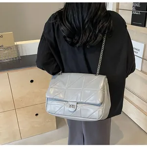 Detail der grauen Stepptasche mit silbernem Drehverschluss und metallischer Kette