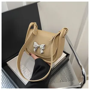 Détail d'un sac à bandoulière en cuir beige avec boucle nœud en métal argenté sur rabat