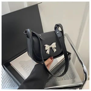 Détail du sac selle noir mat avec boucle en métal argenté et fine bandoulière en cuir