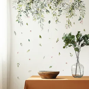 Close-up of watercolor green leaf wall decals on a white wall in a natural living room