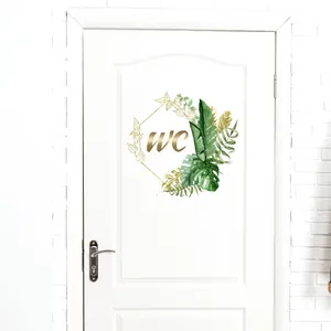 Detailed close-up of a self-adhesive WC door sticker with tropical leaves and golden text