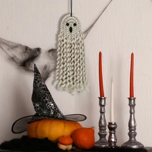 Detailed view of handmade macrame ghost wall hanging with pumpkins and candles