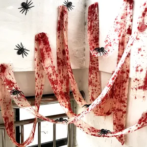 Detail of bloody Halloween gauze with black toy spiders hanging on a staircase wall decor