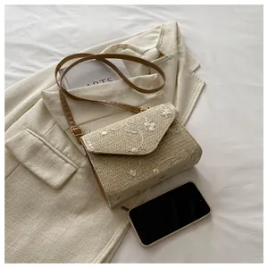 Top-down view of woven straw crossbody bag with floral embroidery on a chic blazer background